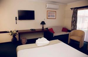 ein Hotelzimmer mit einem Bett, einem Sofa und einem TV in der Unterkunft The Miners Rest Motel in Kalgoorlie