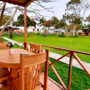 uma mesa e cadeiras de madeira com um parque ao fundo em Apart Hotel El Paraíso de Barranca em Barranca