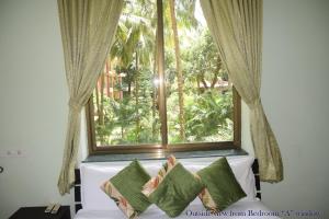 a window with a couch with pillows in front of it at Mango Apartment @ Palolem Garden Estate in Canacona