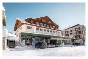 un bâtiment avec des voitures garées dans un parking dans l'établissement Appartements Insieme, à Obertauern