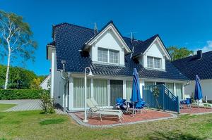 a house with chairs and umbrellas in the yard at Strandglück FH 1 in Zingst
