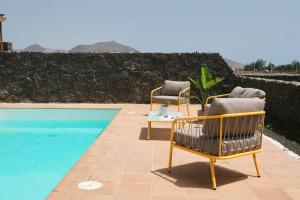 two chairs and a table next to a swimming pool at CASA MOCI in Playa Blanca