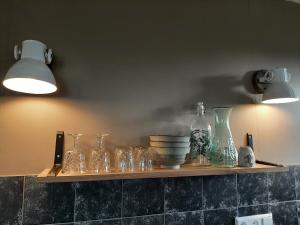 a shelf with glass bottles and bowls on a wall at Appartement Voorhuis en chalet Klein Waterland in Amsterdam
