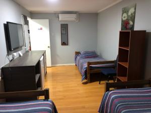 Habitación con 2 camas y TV de pantalla plana. en Residencial la Casa de Millan en Rancagua