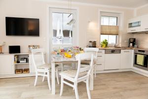 a kitchen with a table with white chairs and a kitchen with at Whg 11 - Sonnencamp in Zingst