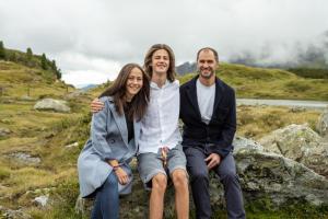 a group of three people sitting on rocks in a field at Appartements Insieme in Obertauern