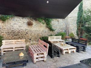 un patio con bancos, mesas y una pared de piedra. en Posada Santa Rita, en Enciso