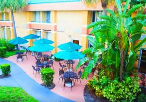 a patio with tables and chairs with blue umbrellas at Bposhtels Orlando Florida Mall in Orlando