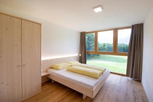 a bedroom with a bed and a large window at Bauernhof Residence Hausergut in Sluderno