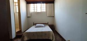 a bedroom with a bed in a room with two windows at Apart Hotel Flomon in Ouro Preto