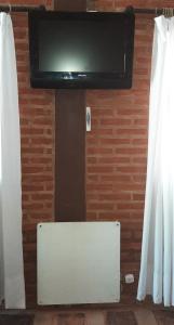 a flat screen tv hanging on a wall with curtains at Cabañas Monoambiente La Foresta, en Mar de las Pampas in Mar de las Pampas