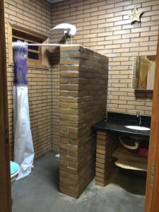 une salle de bain avec un mur de briques et un lavabo dans l'établissement Casa de Campo - Chácara - Lagoa dos Encantos, à Barra Velha