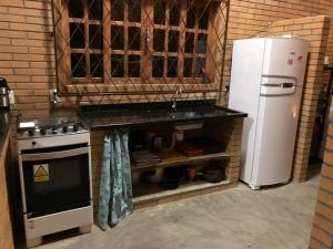 une cuisine avec un évier et un réfrigérateur dans l'établissement Casa de Campo - Chácara - Lagoa dos Encantos, à Barra Velha 21 autres photos