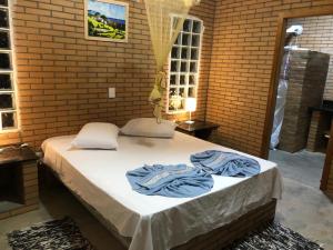 un lit dans une pièce en briques avec des serviettes bleues dessus dans l'établissement Casa de Campo - Chácara - Lagoa dos Encantos, à Barra Velha
