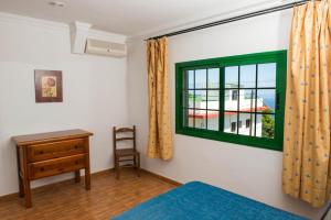 フロンテーラにあるApartamentos la Palmeraの緑の窓とデスクが備わるベッドルーム1室が備わります。
