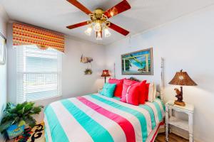 a bedroom with a colorful bed and a ceiling fan at Beach Front #203 in Gulf Shores