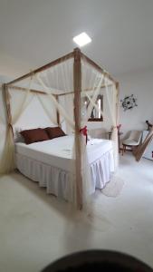a bedroom with a white bed with a canopy at Pousada Sol e Violão in São Miguel do Gostoso