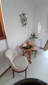 salon z 2 krzesłami, stołem i zegarem w obiekcie Pousada Sol e Violão w mieście São Miguel do Gostoso