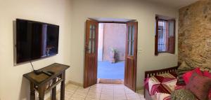 een woonkamer met een televisie en een deur naar een kamer bij º Real Central Suite º in Ouro Preto