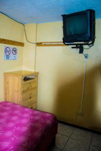 um quarto com uma televisão na parede e uma cama roxa em La Posada Del Viajero em Latacunga
