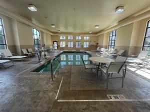 a swimming pool with tables and chairs in a building at Staybridge Suites Lansing-Okemos by IHG in Okemos