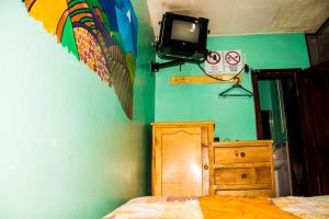 1 dormitorio con 1 cama y TV en la pared en La Posada Del Viajero, en Latacunga