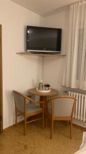 Habitación con mesa, 2 sillas y TV en la pared. en Hotel Gold´ne Krone, en Oppenheim