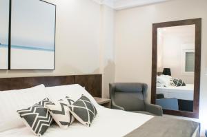 um quarto com uma cama, uma cadeira e um espelho em Hotel Kindermann em Caçador