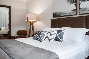 1 dormitorio con 1 cama con sábanas y almohadas blancas en Hotel Kindermann, en Caçador