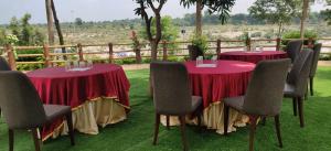 two tables and chairs with red table cloths on the grass at Vrindavan Gopala Resort in Jabalpur