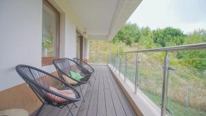 two chairs on a balcony with a view of trees at Coroni Apart 1 Cu Vedere Panoramica Brasov in Braşov