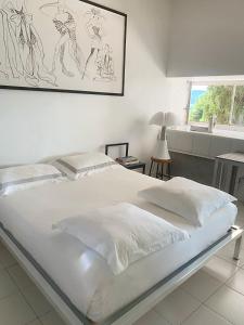 a white bed in a bedroom with a picture on the wall at ÉLÉGANT STUDIO DANS BATIMENT HISTORIQUE in Saint-Tropez