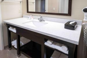 La salle de bains est pourvue d'un lavabo, d'un miroir et de serviettes. dans l'établissement Comfort Suites Fresno River Park, à Fresno