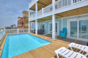 a house with a swimming pool on a deck with chairs at Drift Away in Oak Island