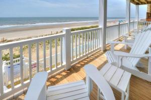 a porch with white chairs and a view of the beach at Drift Away in Oak Island