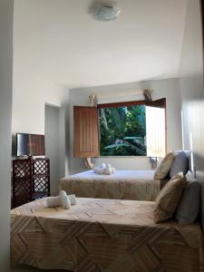sala de estar con 2 camas y ventana en Pousada Lagoa Flat en Morro de São Paulo