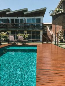 a swimming pool with two chairs and a house at Pousada Rosa Tropicalia in Praia do Rosa