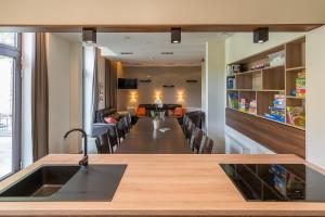 a kitchen with a long table and a living room at Het Dorpshuys - vakantiewoning tot 12 personen in Maaseik