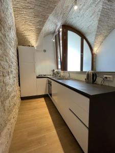eine Küche mit weißen Arbeitsflächen und einer Ziegelwand in der Unterkunft Assisi AD Apartaments - Sorella Luna Boutique Home in Assisi