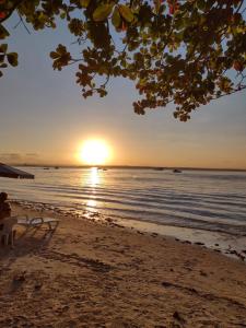 モロ・デ・サンパウロにあるPousada Lagoa Flatのベンチに座った人と一緒にビーチでの夕日