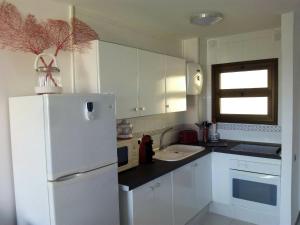 cocina con armarios blancos y nevera blanca en Apartamento Playa de las vistas Torres del Sol C3 308, en Arona