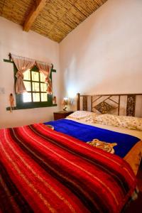 a bedroom with a bed with a red blanket at Hosteria la granja in Huacalera