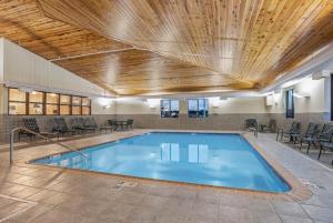 a swimming pool with a wooden ceiling and tables and chairs at La Quinta by Wyndham Norwich-Plainfield-Casino in Plainfield