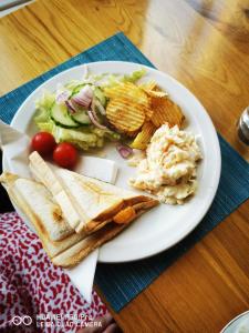 um prato branco de comida com salada e batatas fritas em oddfellowsbandb em Blythe