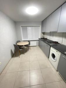 a kitchen with a table and a stove and a washing machine at Апартаменты Проспект Победы 101 in Chernihiv