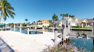 a dock with houses and palm trees next to a body of water at Luxury Rental Walkable To Beach With Wide Water Views I Pet Friendly in Henry Key