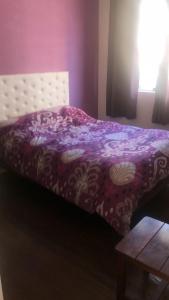a bed with a purple comforter and a table at varesse house in Mar del Plata
