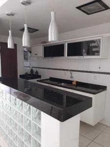 una cocina con encimera negra y luces colgantes en Casa Estelar en Cabo Frío