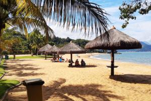a beach with umbrellas and people sitting on the sand at Condomínio Sítio Bom - Mangaratiba - Costa Verde in Mangaratiba