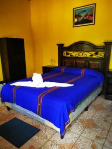 a bed in a room with a blue comforter at Hostal Oasis The Traveler in Lanquín